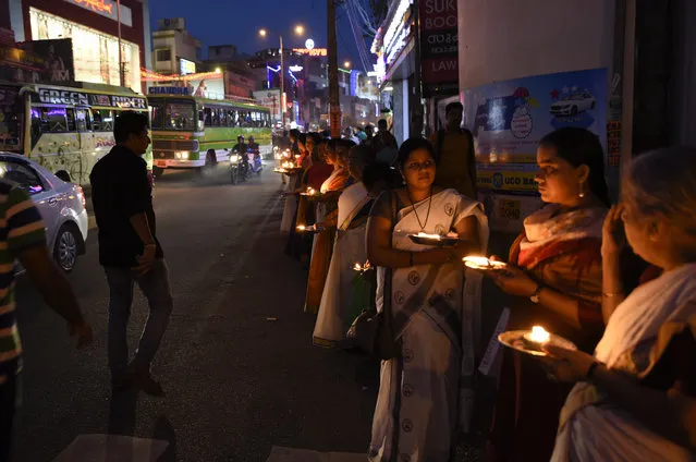 Hindu women hold oil lamps by a roadside as they protest a Supreme Court verdict allowing the entry of women of menstruating age at the Sabarimala temple, one of the world's largest Hindu pilgrimage sites, In Thiruvanathapuram, Kerala, India, Wednesday, December 26, 2018. As part of a statewide protest Wednesday, devotees lit lamps for 30 minutes by major roads from the northern end to the southern end the state of Kerala. (Photo by R.S. Iyer/AP Photo)