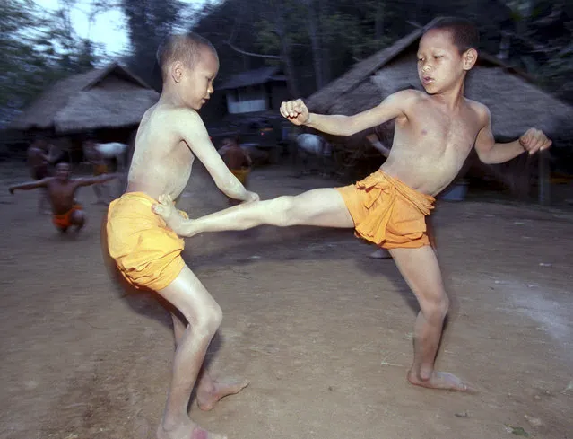 In this March 19, 2002, file photo, two novice Buddhist monks practice Muay Thai (Thai kickboxing) during a morning training session at the Golden Horse Monastery in northern Thailand. The death of a 13-year-old boy who was knocked out during a Muay Thai boxing match in Thailand has sparked debate over whether to ban child boxing. (Photo by David Longstreath/AP Photo)