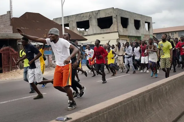 Congolese sportsmen run towards the main stadium in Kinshasa, Congo, Tuesday January 8, 2019, to participate in a general boxing and martial arts competition. As Congo anxiously awaits the outcome of the presidential election, many in the capital say they are convinced that the opposition won and that the delay in announcing results is allowing manipulation in favor of the ruling party. (Photo by Jerome Delay/AP Photo)