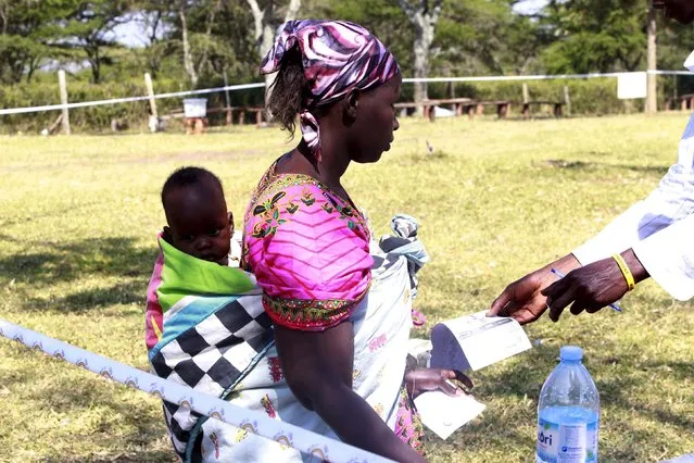 A mother prepares to cast her ballot at a polling station during the presidential elections in Kirihura in western Uganda, February 18, 2016. Ugandans start casting votes on Thursday to decide whether to give Yoweri Museveni, in power for three decades, another term in office. (Photo by James Akena/Reuters)