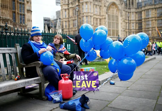 An Anti-Brexit demonstrator sits next to a Pro-Brexit demonstrator outside the Houses of Parliament, in Westminster, London, Britain on January 29, 2019. (Photo by Henry Nicholls/Reuters)