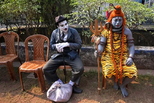 Artists dressed as Charlie Chaplin (L) and Hindu lord Shiva wait to perform during a programe organised to promote and create awareness about the traditional folk art form of polymorphic “Bahuroopiya” in Kolkata on December 28, 2023. (Photo by Dibyangshu Sarkar/AFP Photo)