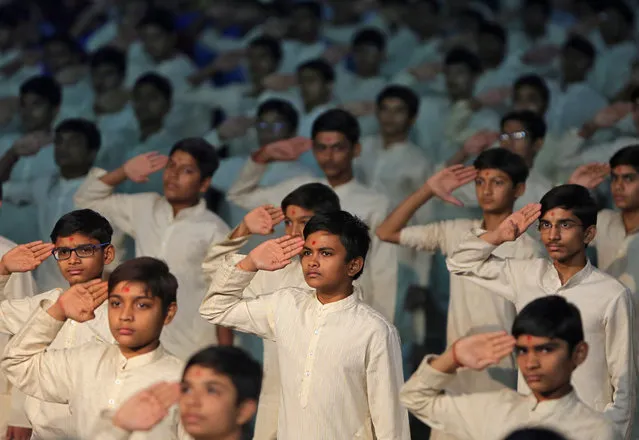 Students salute before a vigil to pay tribute to Central Reserve Police Force (CRPF) personnel who were killed after a suicide bomber rammed a car into a bus carrying them in south Kashmir on Thursday, inside a temple in Ahmedabad, India, February 15, 2019. (Photo by Amit Dave/Reuters)