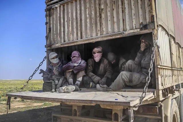 A picture taken on February 20, 2019, shows a truck carrying men, identified as Islamic State group fighters who surrendered to Kurdish-led Syrian Democratic Forces (SDF), as they are transported out of IS's last holdout of Baghouz in Syria's northern Deir Ezzor province. A convoy of trucks evacuated dozens of people from the Islamic State group's last Syria redoubt, bringing US-backed forces closer to retaking the final patch of their 2014 “caliphate”. The implosion of the jihadist proto-state which once spanned swathes of Syria and neighbouring Iraq has left Western nations grappling with how to handle citizens who left to join IS. (Photo by Bulent Kilic/AFP Photo)