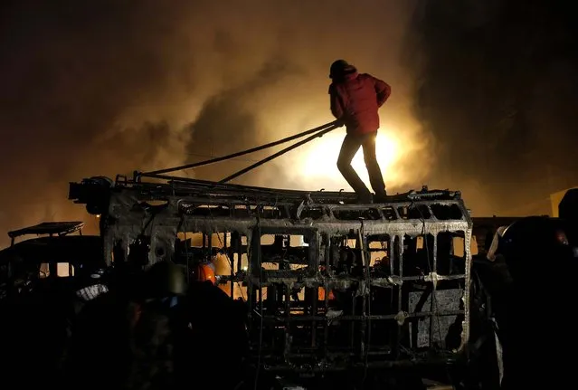 A protester stands on top of a barricade during clashes with police in Kiev, Ukraine, on January 21, 2014. After a night of vicious street battles, anti-government protesters and police clashed again in Ukraine's capital. (Photo by Sergei Grits/Associated Press)