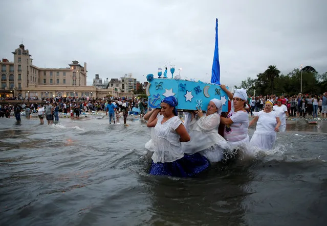 Devotees of the Afro-Brazilian goddess of the sea Iemanja pay tribute on Iemanja Day with offerings, to ask for good health and luck in love and work, at Ramirez beach in Montevideo February 2, 2017. (Photo by Andres Stapff/Reuters)