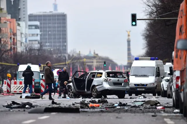 Rescuers and police officers work around a car after a blast caused by an explosive device killed its driver travelling down a street in central Berlin on March 15, 2016. The blast occurred during peak-hour traffic on Bismarckstrasse, within sight of the Victory Column monument, leaving the front of the car severely dented after it flipped over, while debris was strewn a few metres away. (Photo by Odd Andersen/AFP Photo)