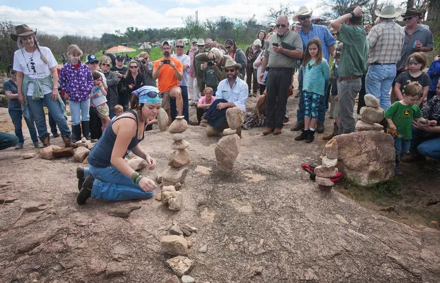 Festival  goers surround Tara Long from Mason, TX as she works to complete a balanced rock stack in two minutes for competition. Her stack tumbled a few seconds later forcing her to start again Saturday March 12, 2016. Several contests were held at the Llano environmental Arts Festival on Saturday including height stacking, arches and artistic. (Photo by Nell Carroll/American-Statesman)