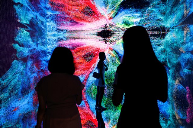 Visitors are pictured in front of an immersive art installation titled “Machine Hallucinations – Space: Metaverse” by media artist Refik Anadol, which will be converted into NFT and auctioned online at Sotheby's, at the Digital Art Fair, in Hong Kong, China on September 30, 2021. (Photo by Tyrone Siu/Reuters)