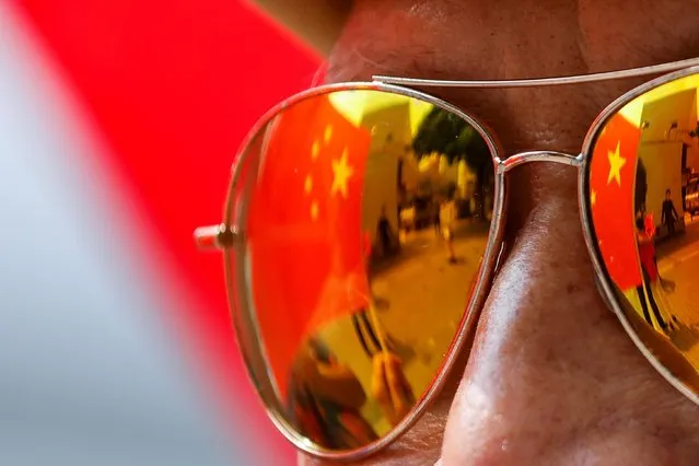 The reflection of the Chinese flags are seen in the glasses of a supporter on Chinese National Day, in Hong Kong, China, October 1, 2021. (Photo by Tyrone Siu/Reuters)
