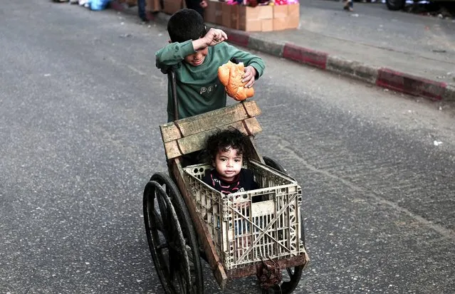A boy pushes a child in a makeshift buggy in Rafah, on the southern Gaza Strip on February 28, 2024, amid ongoing battles between Israel and the Palestinian militant group Hamas. (Photo by AFP Photo)