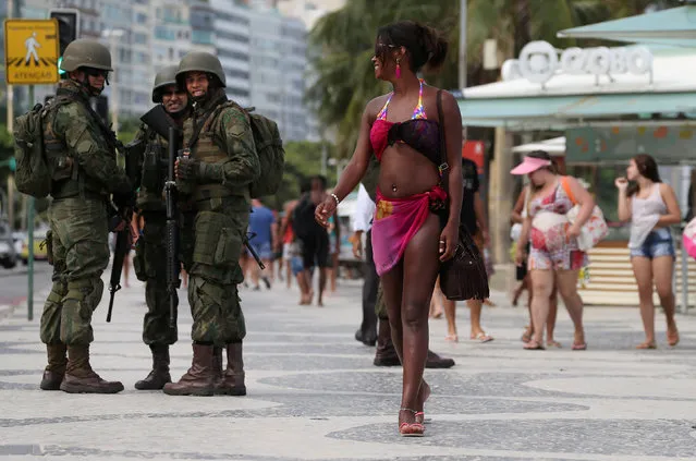 Brazilian navy soldiers watch a woman as they patrol the area at the Copacabana Beach before carnival festivities in Rio de Janeiro, Brazil February 14, 2017. (Photo by Sergio Moraes/Reuters)
