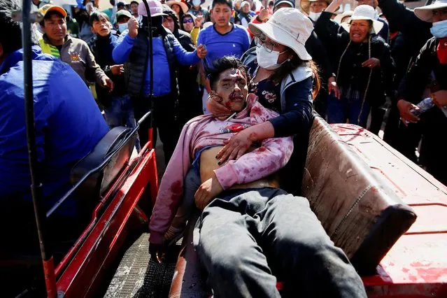 Demonstrators assist an injured man during a clash with security forces, during a protest demanding early elections and the release of jailed former President Pedro Castillo, near the Juliaca airport, in Juliaca, Peru on January 9, 2023. (Photo by Hugo Courotto/Reuters)