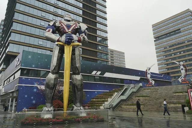 In this April 2, 2019, photo, people walk by a giant robot statue at a virtual reality “base” in Nanchang, China. The city is trying to position itself as a leader in VR technology, opening one of the largest virtual reality theme parks in the world to get ordinary people excited about the technology. It's part of China's long-term bet that VR will come into widespread use. (Photo by Dake Kang/AP Photo)