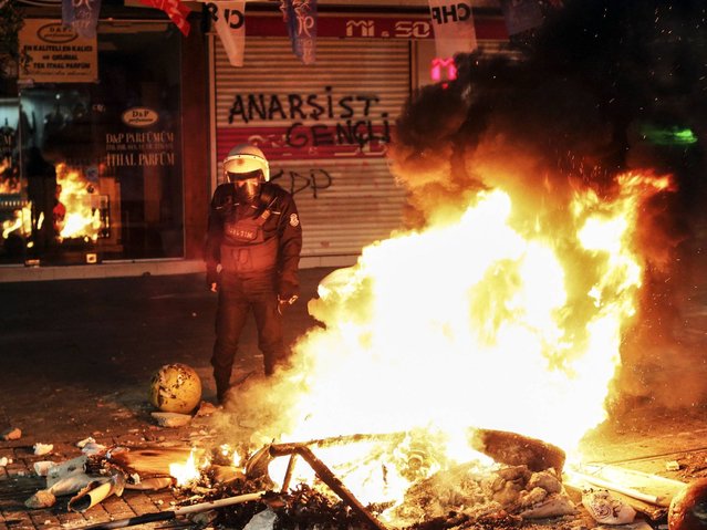 A riot police stands near a burning barricade during clashes with riot police in Kadikoy, on the Anatolian side of Istanbul. (Photo by Gurcan Ozturk/AFP Photo)