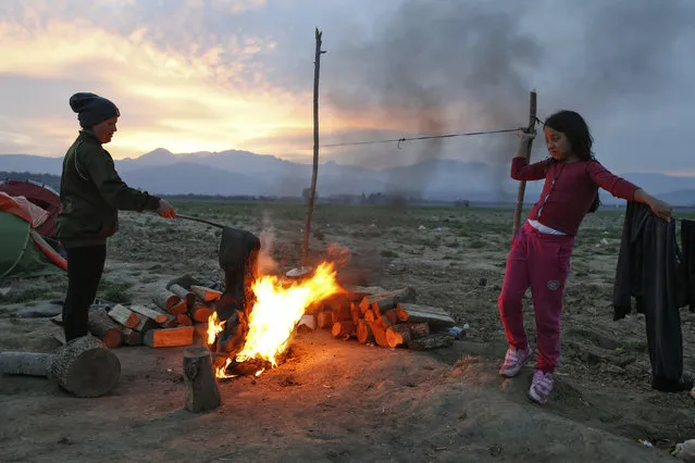 A woman and a child make a bonfire at a makeshift camp for migrants and refugees at the Greek-Macedonian border near the village of Idomeni, Greece, April 1, 2016. (Photo by Marko Djurica/Reuters)