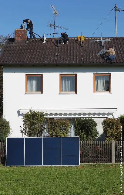 Workers install solar power modules for producing heat on the roof of a house