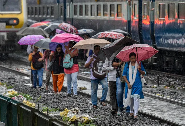 People walk on the railway tracks as heavy monsoon rains hit the local train services near Sion on July 1, 2019 in Mumbai, India. Heavy rains for last four days led to trains disruptions, flooded roads, traffic jams and flight delays. At least 250 suburban services, including 100 on WR, were cancelled and several others ran delayed all day on both CR and WR. (Photo by Kunal Patil/Hindustan Times via Getty Images)
