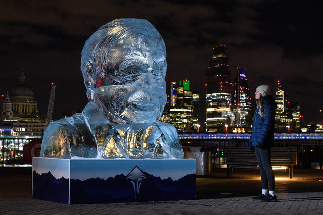 Emily Gander, from London, looks at a 2-metre-tall ice-sculpture of Sir David Attenborough on Wednesday February 10, 2021, as it is unveiled on London's Southbank as part of TENZING's Take Action campaign, to demonstrate the rate of the Arctic sea ice melt, caused by one person's carbon emissions in the UK every fortnight. (Photo by Matt Crossick/PA Wire Press Association)