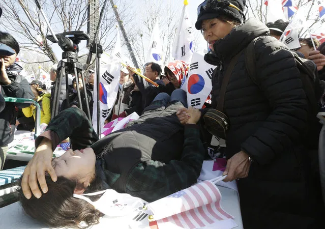 A fainted supporter of South Korean President Park Geun-hye lies on a table during a rally opposing her impeachment near Constitutional Court in Seoul, South Korea, Friday, March 10, 2017. In a historic ruling Friday, South Korea's Constitutional Court formally removed the impeached president from office over a corruption scandal that has plunged the country into political turmoil, worsened an already-serious national divide and led to calls for sweeping reforms. (Photo by Ahn Young-joon/AP Photo)