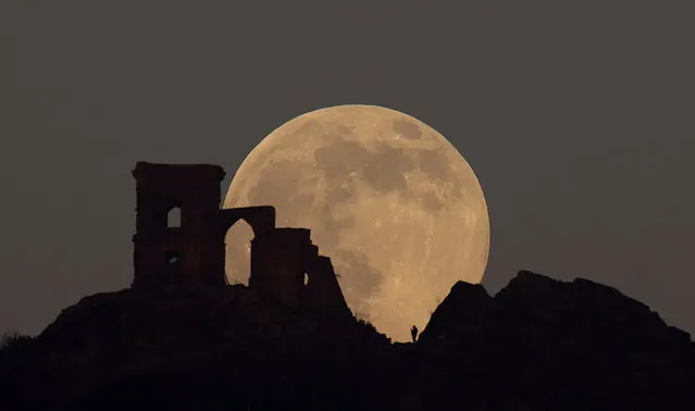 The Wolf Moon rises over Mow Cop Folly, Mow Cop, Britain, January 17, 2022. (Photo by Carl Recine/Reuters)