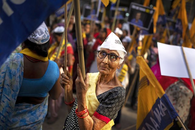 An elderly supporter of Aam Admi Party holds a party flag during a roadshow by Sunita Kejriwal, wife of the jailed Party leader and Delhi Chief Minister Arvind Kejriwal, ahead of the third round of polling in the six-week long national election in New Delhi, India, Saturday, April 27, 2024. (Photo by Altaf Qadri/AP Photo)
