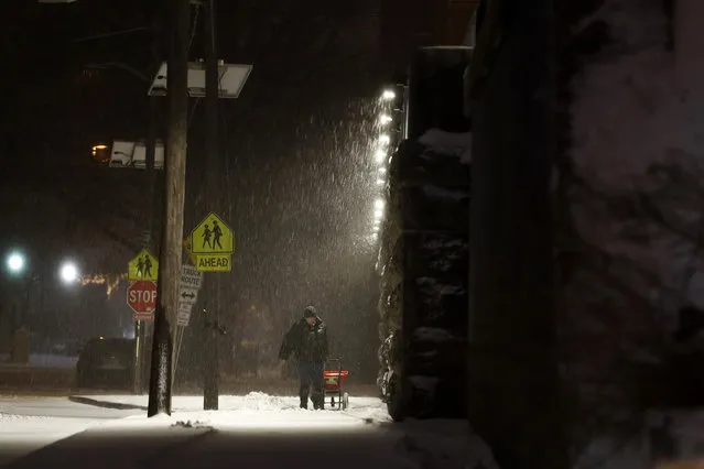 A man salts a sidewalk during a snowstorm, Tuesday, March 14, 2017, in Jersey City, N.J. (Photo by Julio Cortez/AP Photo)