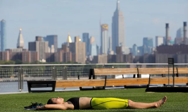 A woman lies in Domino Park as a heatwave continues to affect the region in Brooklyn, New York, U.S., July 21, 2019. (Photo by Andrew Kelly/Reuters)