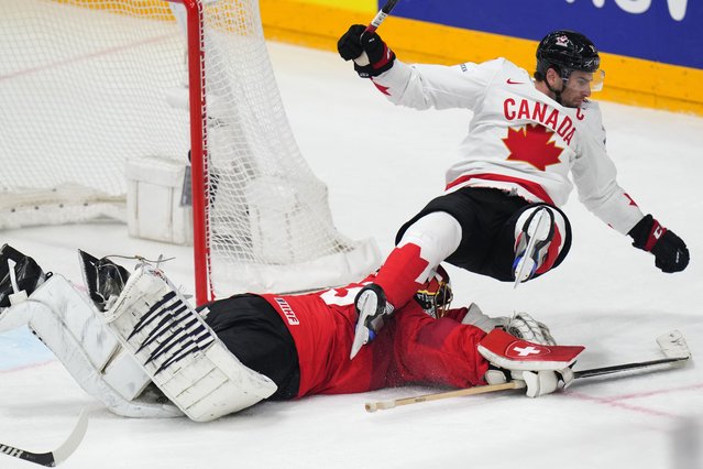 Canada's John Tavares falls over Switzerland's goalkeeper Leonardo Genoni during the preliminary round match between Canada and Switzerland at the Ice Hockey World Championships in Prague, Czech Republic, Sunday, May 19, 2024. (Photo by Petr David Josek/AP Photo)