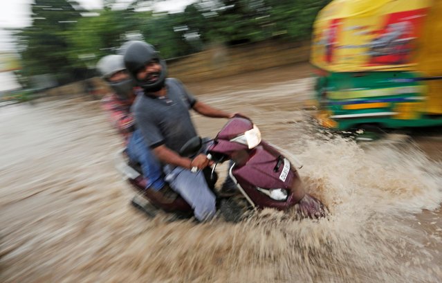 Men ride a scooter through a flooded street after heavy rains in New Delhi, India, August 6, 2019. (Photo by Adnan Abidi/Reuters)