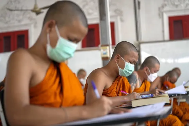Buddhist monks wearing face masks to help protect themselves from the coronavirus, take a test for the liturgical Pali language at Wat Molilokayaram in Bangkok, Thailand, Thursday, January 20, 2022. (Photo by Sakchai Lalit/AP Photo)