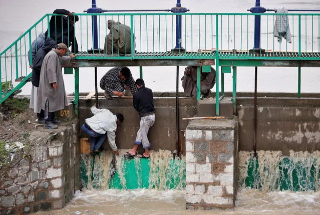 People try to stop water flowing through the gate of a flood channel after incessant rains in Srinagar April 7, 2017. (Photo by Danish Ismail/Reuters)