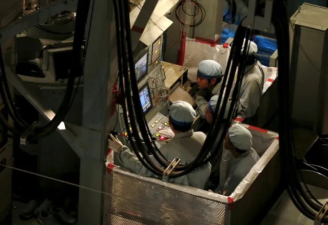 Employees of Kyushu Electric Power Co. ride on a special crane during an operation inserting fuel rods into a reactor vessel inside the No. 1 reactor building at's Sendai nuclear power station in Satsumasendai, Kagoshima prefecture, Japan, July 8, 2015. (Photo by Issei Kato/Reuters)