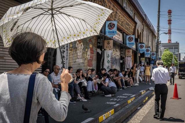 People rest in the shade at the Tsukiji outer market in Tokyo on June 12, 2024. (Photo by Yuichi Yamazaki/AFP Photo)