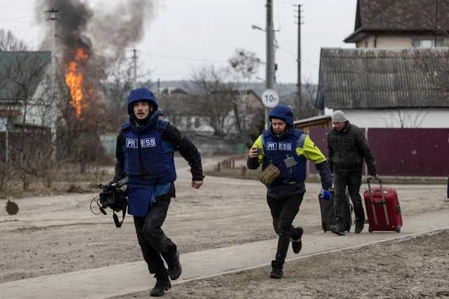 Journalists run for cover after heavy shelling on the only escape route used by locals, while Russian troops advance towards the capital, in Irpin, near Kyiv, Ukraine on March 6, 2022. (Photo by Carlos Barria/Reuters)