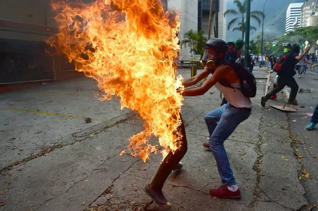 A demonstrator catches fire after the gas tank of a police motorbike exploded during clashes in a protest against Venezuelan President Nicolas Maduro, in Caracas on May 3, 2017. (Photo by Ronaldo Schemidt/AFP Photo)