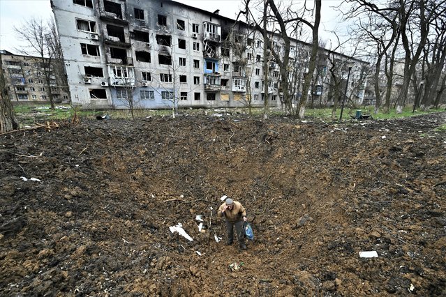 An elderly man with poor eyesight stands up after falling into an explosion crater in the frontline town of Avdiivka, Donetsk region on April 4, 2023, amid the Russian invasion of Ukraine. (Photo by Genya Savilov/AFP Photo)