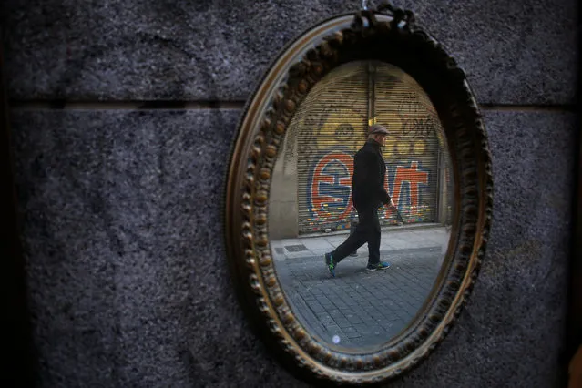A man is reflected in a mirror as he walks at La Latina neighbourhood in Madrid, Spain February 8, 2017. (Photo by Juan Medina/Reuters)
