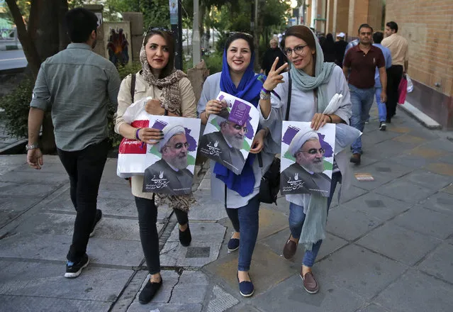 In this photo taken on Wednesday, May 17, 2017, supporters of Iranian President Hassan Rouhani hold posters with his image, during a street campaign ahead the May 19 presidential election in downtown Tehran, Iran. Iranian President Hassan Rouhani staked his political future on opening Iran ever so slightly to the outside world and overcoming hard-liners' opposition to secure a historic nuclear deal in exchange for relief from crippling sanctions. (Photo by Vahid Salemi/AP Photo)