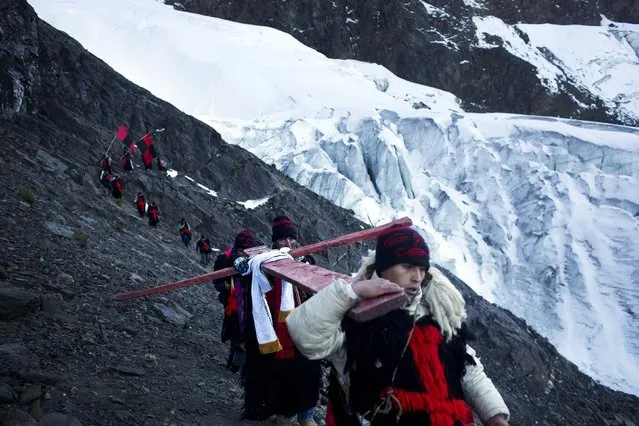 In this May 24, 2016 photo, men dressed as mythical half-man, half-bear creatures called “Ukukus”, descend the Qullqip'unqu mountain glacier carrying a cross on the last day of the syncretic festival Qoyllur Rit’i, translated from the Quechua language as Snow Star, in the Sinakara Valley, in Peru's Cusco region. The ukukus also used to cut away blocks of ice from the glacier to bring down to share with the community in the belief that the melted held magical healing powers, but no longer noting a decline in the size of the glaciers because of warming trends. (Photo by Rodrigo Abd/AP Photo)