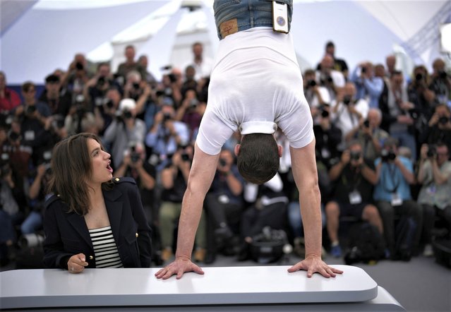 French actress Billie Blain, left, reacts as French-Israeli actor and comedian Tom Mercier performs a handstand at the photo call for the film “Le Regne animal” at the 76th international film festival, Cannes, southern France, Thursday, May 18, 2023. (Photo by Daniel Cole/AP Photo)