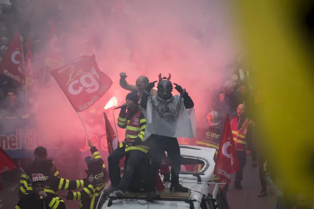 Protesters light flares during a march in Marseille, southern France, Tuesday, December 17, 2019. Workers at the Eiffel Tower, teachers, doctors, lawyers and people from across the French workforce walked off the job Tuesday to resist a higher retirement age, or to preserve a welfare system they fear their business-friendly president wants to dismantle. (Photo by Daniel Cole/AP Photo)
