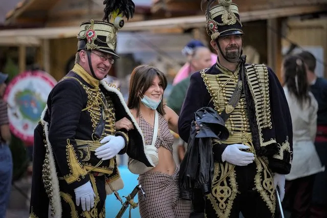 A young female poses with men wearing vintage Hungarian military uniforms at a fair outside the St. Stephen's Basilica in Budapest, Hungary, Friday, September 10, 2021. Pope Francis is making his first foreign trip since undergoing intestinal surgery in July. His four-day visit to Hungary and Slovakia starting Sunday will not only test his health but also provide what may be one of the most awkward moments of his papacy – a meeting with Hungarian Prime Minister Viktor Orban, the sort of populist, right-wing leader Francis scorns. (Photo by Vadim Ghirda/AP Photo)