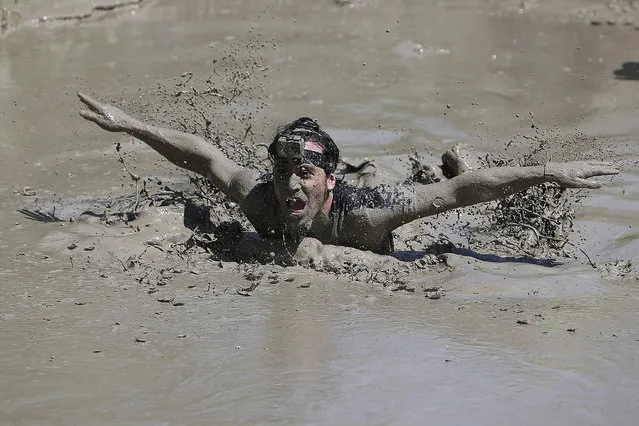 A participant swims to cross a mud pool during the Mud Day athletic event at El Goloso Military base on the outskirts of Madrid, Spain, Saturday, June 11, 2016. (Photo by Paul White/AP Photo)