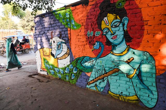 A woman walks past murals painted by artists from “Delhi Street Art” group at the Raghubir Nagar slum in New Delhi on December 2, 2019. (Photo by Sajjad Hussain/AFP Photo)