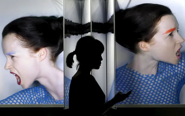 A woman holding her mobile phone walks past a display window outside a cosmetic company at Tokyo's Ginza shopping district in Japan, July 20, 2015. (Photo by Yuya Shino/Reuters)