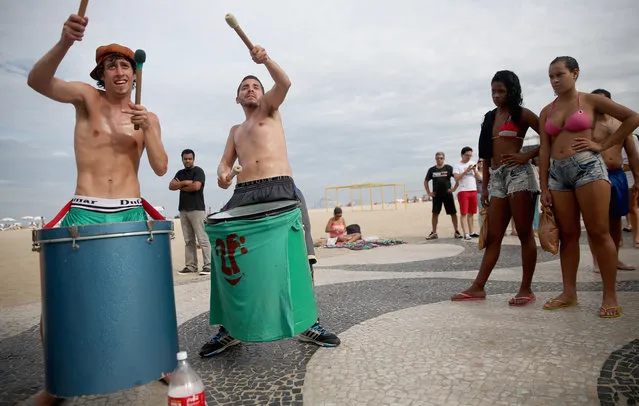 Argentine drummers from the band La Fantastica perform as Brazilians (R) watch on Copacabana Beach on July 7, 2014 in Rio de Janeiro, Brazil. Brazil plays Germany tomorrow in the first semi-final match of the 2014 FIFA World Cup while Argentina faces the Netherlands Wednesday. (Photo by Mario Tama/Getty Images)