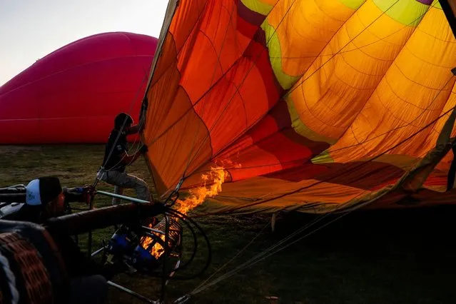 A man warms up the air inside a hot air balloon during a hot air balloon festival held in Penaflor, on the outskirts of Santiago, on February 4, 2022. (Photo by Javier Torres/AFP Photo)