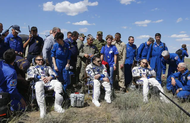 The International Space Station crew, from left, Britain's Tim Peake, Russia's Yuri Malenchenko and Tim Kopra of US, surrounded by ground personnel, rest shortly after landing near the town of Dzhezkazgan, Kazakhstan, Saturday, June 18, 2016. (Photo by Shamil Zhumatov/Pool Photo via AP Photo)