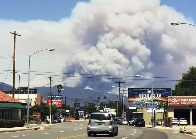 Towering columns of smoke rise from two wildfires on the San Gabriel Mountains are viewed from Pasadena, Calif., Monday, June 20, 2016. The wildfires several miles apart devoured hundreds of acres of brush on steep slopes above foothill suburbs erupted in Southern California as an intensifying heat wave stretching from the West Coast to New Mexico blistered the region with triple-digit temperatures. (Photo by Beth Harris/AP Photo)